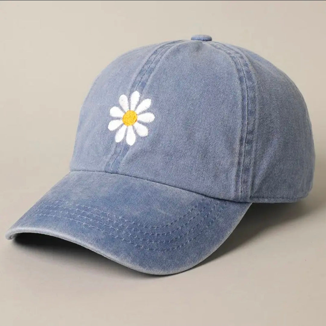 Blue denim cap with a white daisy embroidered on a beige background