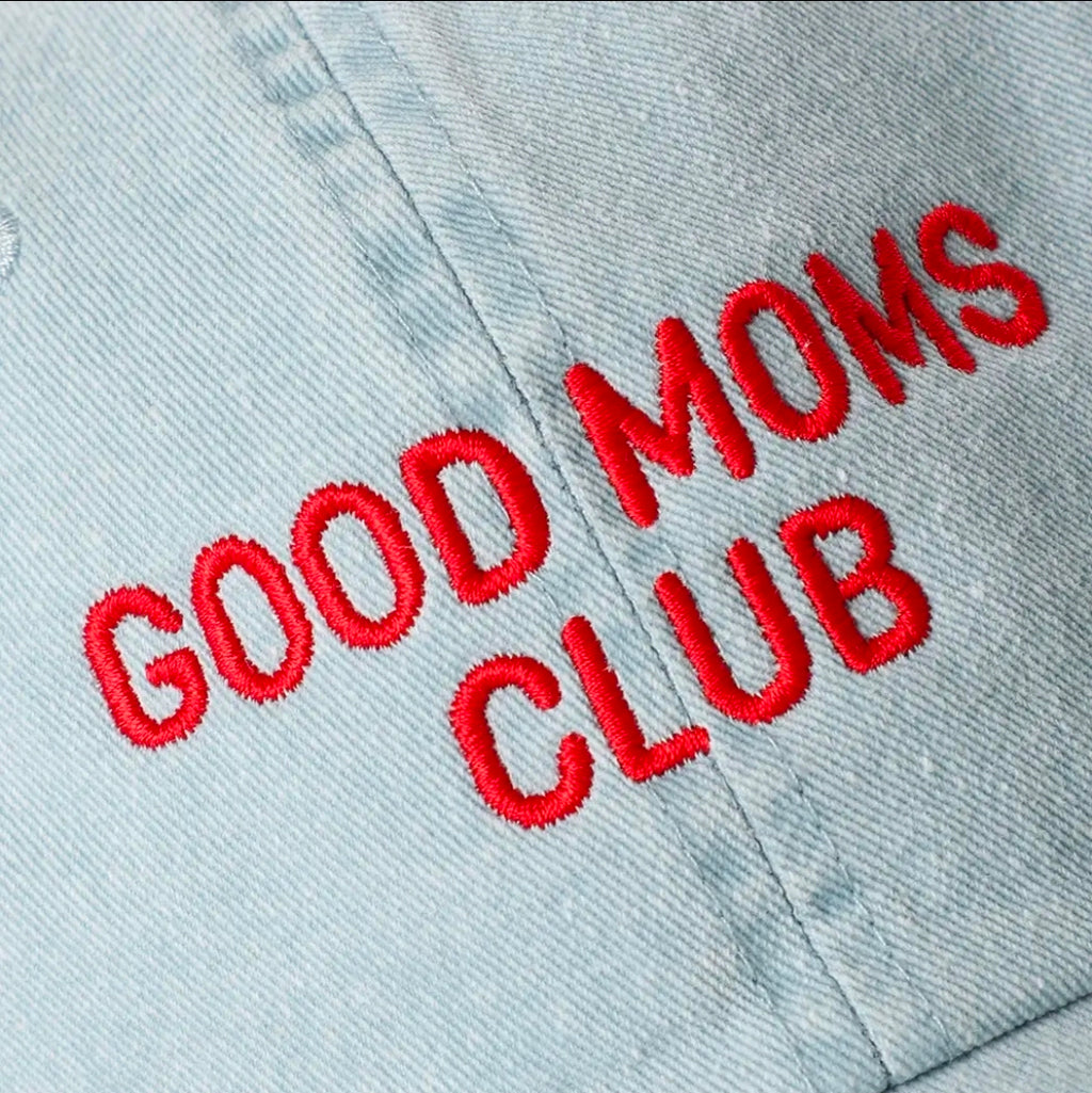 Embroidered text 'GOOD MOMS CLUB' on a light denim background