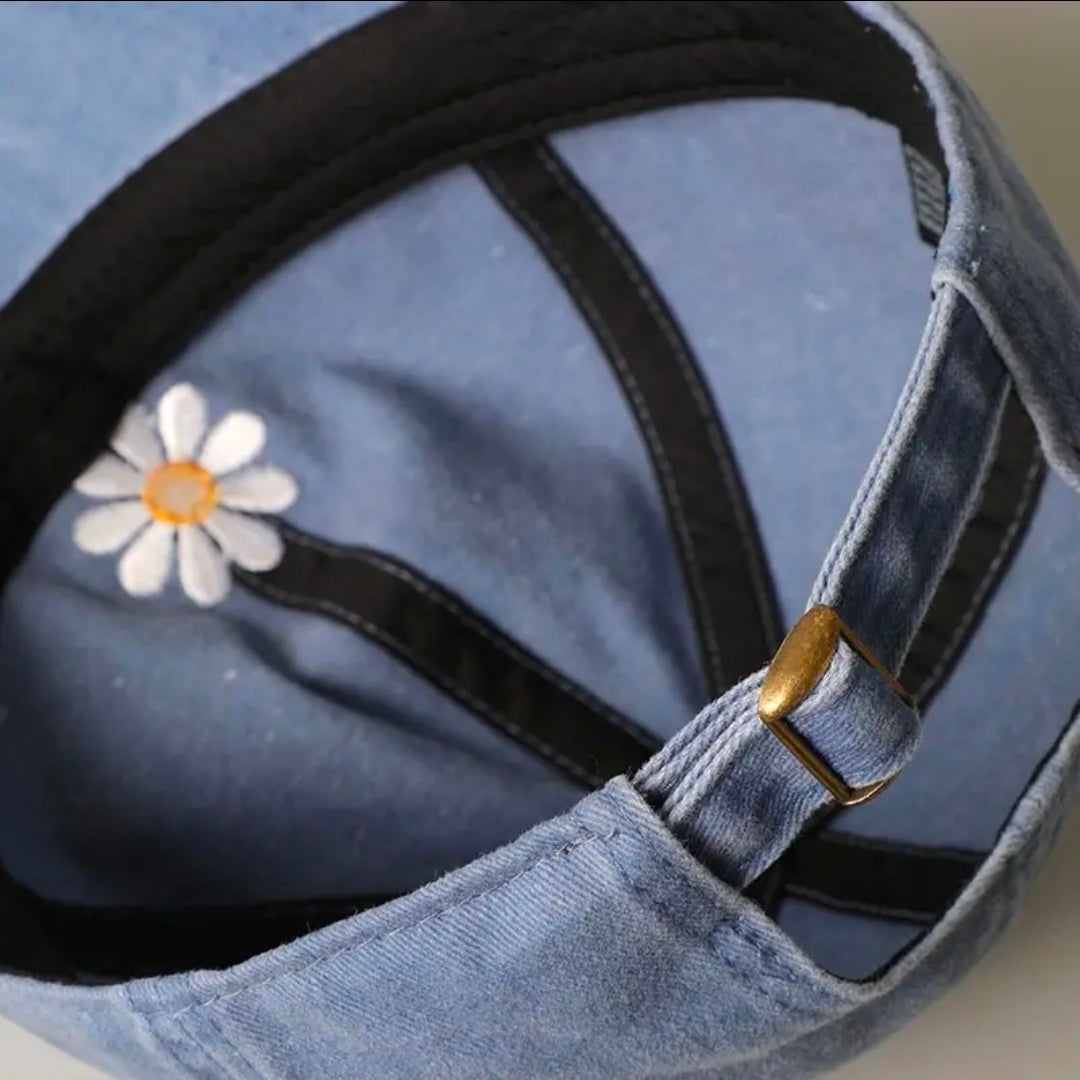 Blue denim bag with a white daisy patch and gold buckle on a light blue background