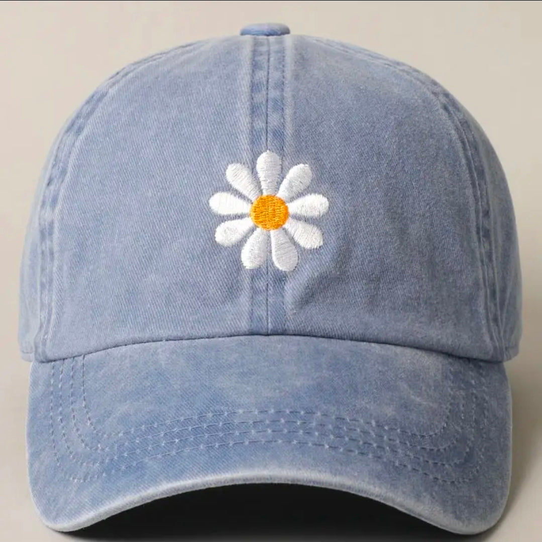 Blue cap with a white daisy embroidered on it against a beige background