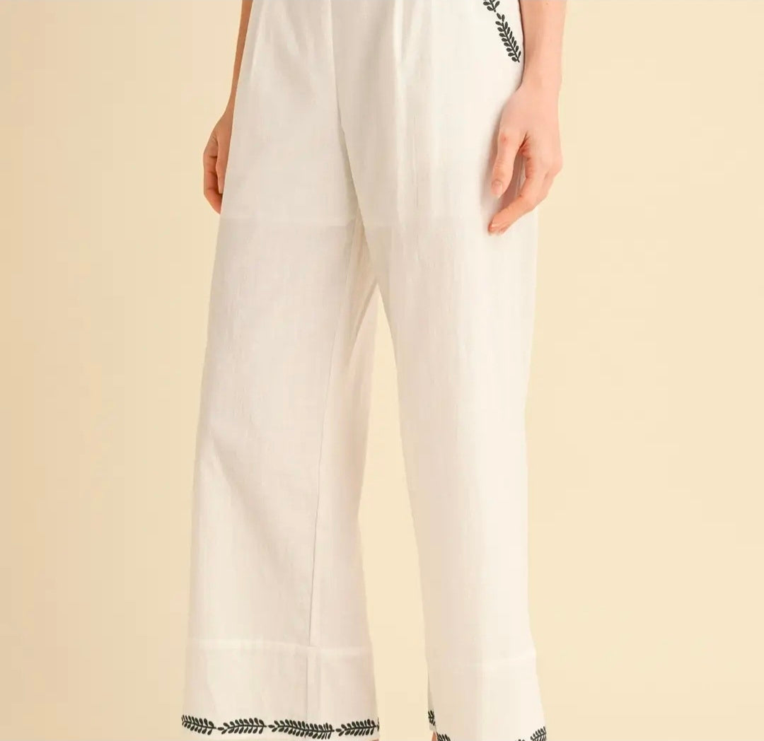 White pants with black trim on a beige background
