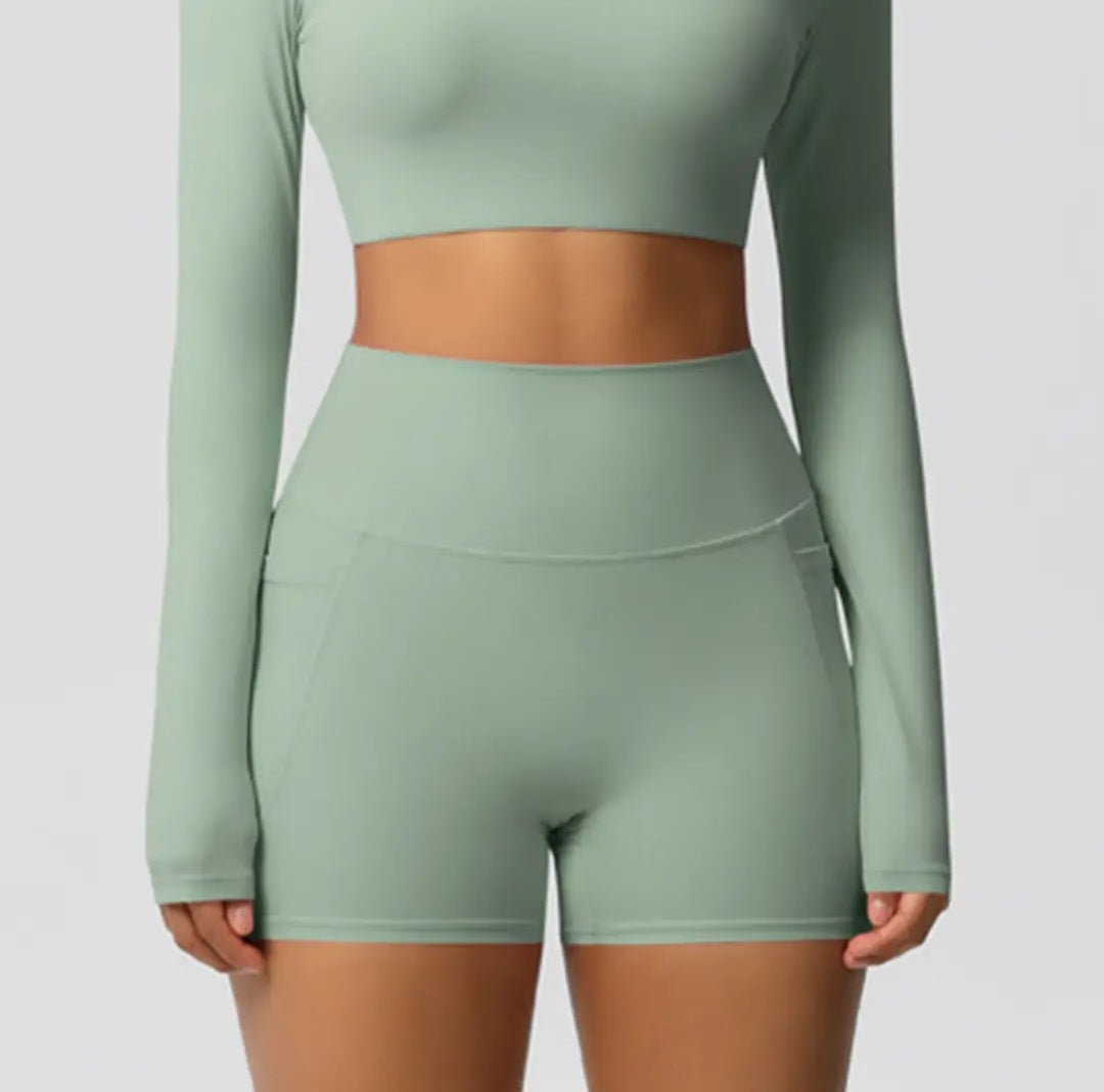 Green athletic outfit with long-sleeve top and shorts on a plain background