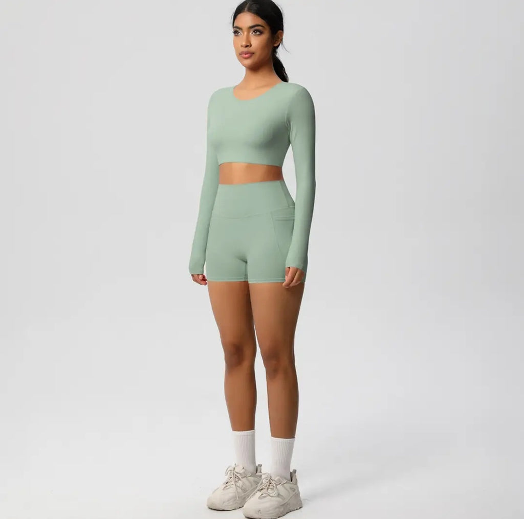 Woman wearing a green long-sleeve top and shorts set on a white background