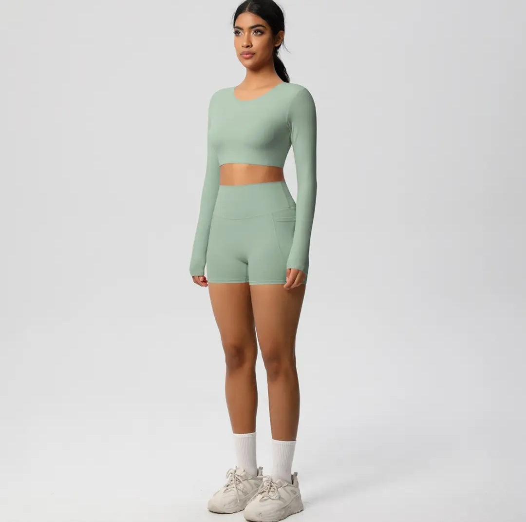 Woman wearing a green long-sleeve top and shorts set on a white background