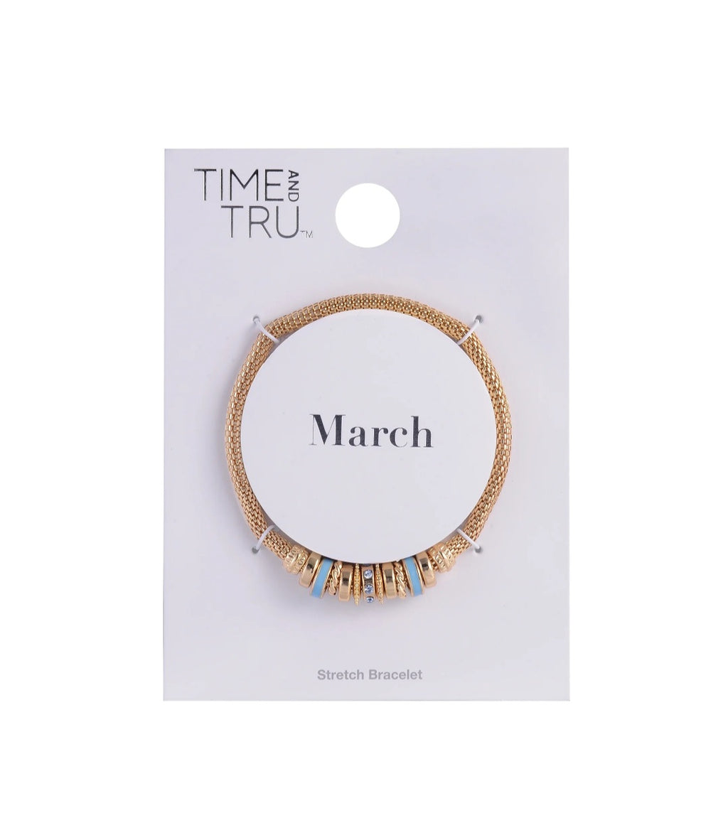 Gold stretch bracelet on a 'Time Tru' branded card with 'March' text on a white background