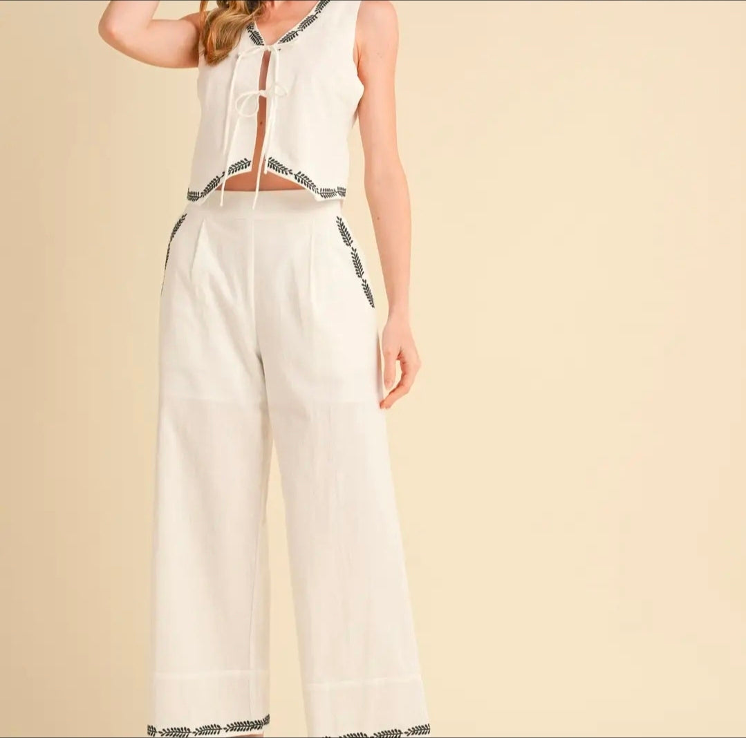 White jumpsuit with black trim on a beige background