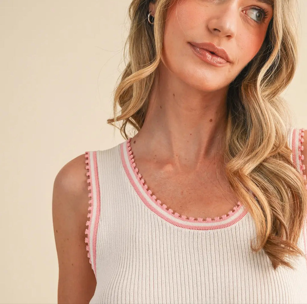 Woman wearing a white tank top with pink trim against a beige background