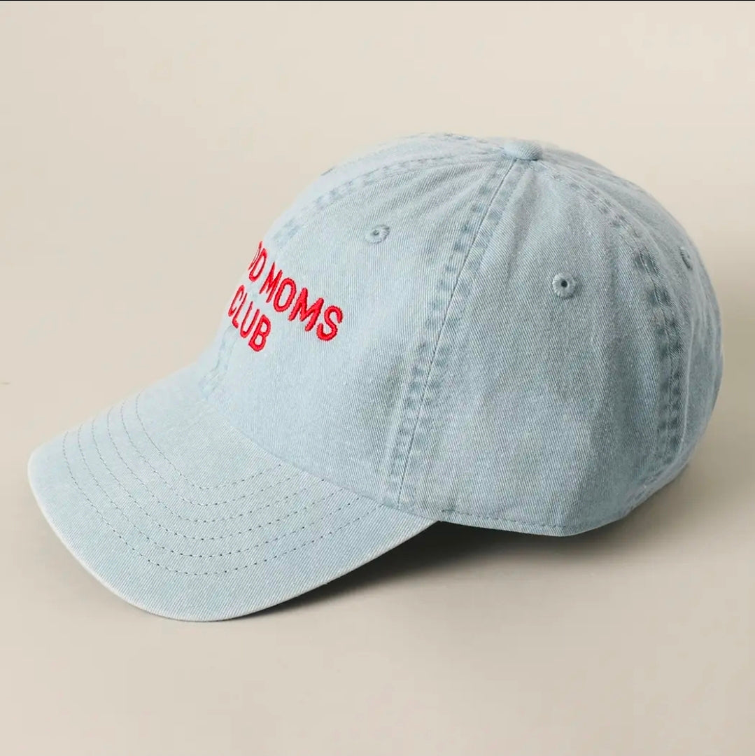 Light blue cap with red text 'GOOD MOMS CLUB' on a beige background